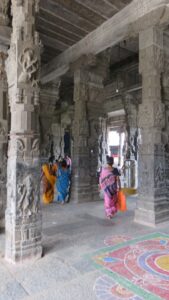 Interior de un templo del sur de la India con columnas y dibujos de colores en el suelo